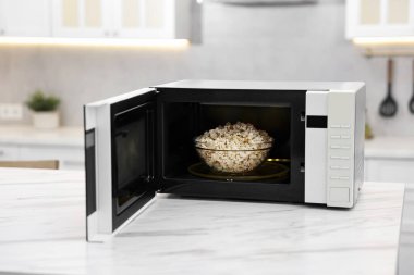 Mikrodalga fırını aç. Mutfaktaki beyaz mermer masada patlamış mısır var.