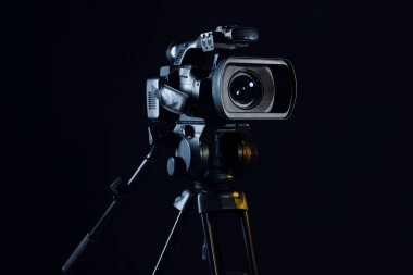 Siyah arka planda tripodu olan modern video kamera