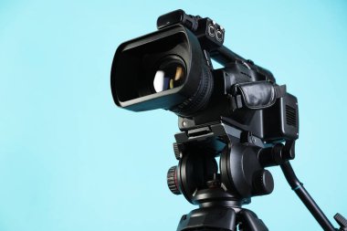 Açık mavi arka planda modern video kamera, yakın plan. Metin için boşluk
