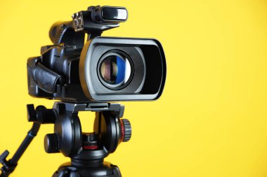 Sarı arka planda modern video kamera, yakın plan. Metin için boşluk