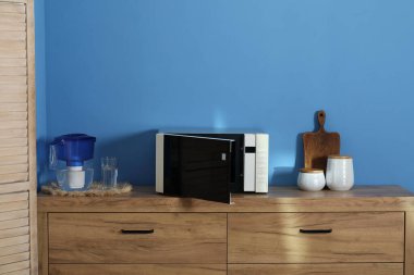 Closed microwave oven and kitchen utensils on wooden cabinet indoors