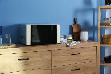 Kapalı mikrodalga fırın, lazanya ve mutfak gereçleri kapalı dolapta.