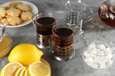 Gri desenli masada servis edilen metal tutacaklı çay bardakları.