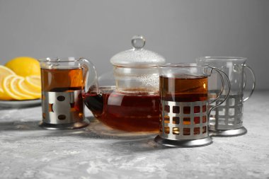 Gri desenli masada servis edilen metal tutacaklı çay bardakları.