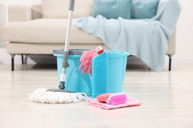 İçerideki ahşap zeminde temizlik malzemesi olan ip ve kova.