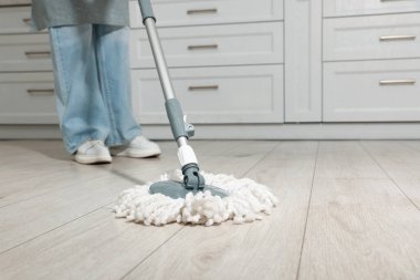 Evdeki yerleri paspasla temizleyen kadın, yakın plan. Metin için boşluk