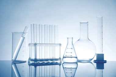 Ayna yüzeyinde ışık arkaplanına karşı sıvı bulunan laboratuvar camları