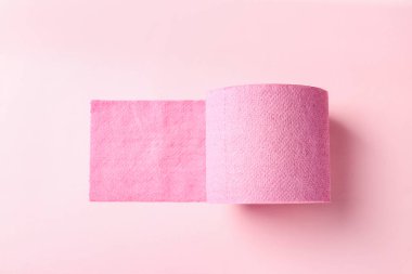 Açık pembe zemin üzerinde renkli tuvalet kağıdı rulosu, üst görünüm