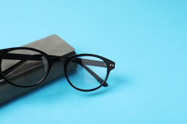 Açık mavi arka planda gözlüklü şık bir çanta, yakın plan. Metin için boşluk