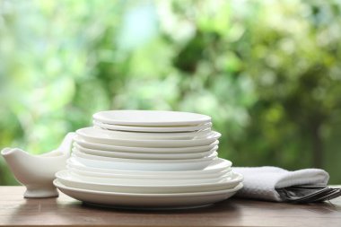 Clean dishware on wooden table against blurred background. Space for text