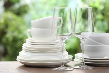 Clean dishware on wooden table against blurred background