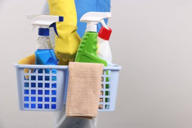 Arka planda temizlik malzemesi sepeti olan bir kadın, yakın plan. Metin için boşluk