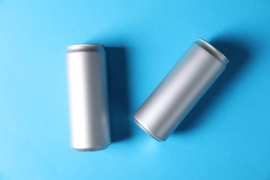 Açık mavi arka planda iki teneke kutu, üst görünümde.