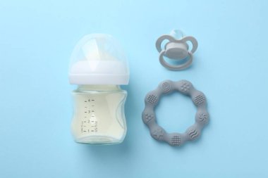 Açık mavi zemin üzerinde süt, ip ve emzik ile beslenme şişesi düz yatıyordu