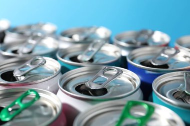 Açık mavi arka planda birçok alüminyum içecek kutusu, yakın plan