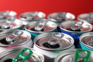 Kırmızı arka planda birçok alüminyum içecek kutusu, yakın plan