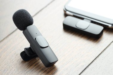 Lavalier mikrofon ve ahşap masada kablosuz alıcısı olan akıllı telefon.