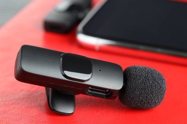 Lavalier mikrofon ve kırmızı defterde kablosuz alıcısı olan akıllı telefon.