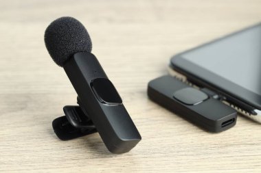 Lavalier mikrofon ve ahşap masada kablosuz alıcısı olan akıllı telefon.