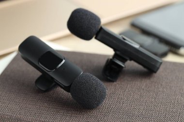 Lavalier mikrofonlar ve defter masanın üstünde, yakın plan.