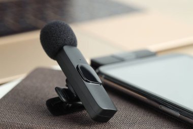 Lavalier mikrofon, kablosuz alıcı ve not defteri olan akıllı telefon, yakın plan.