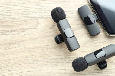 Lavalier mikrofonlar ve ahşap masada kablosuz alıcısı olan akıllı telefon. Metin için boşluk