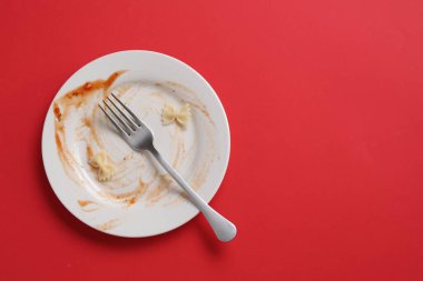 Kirli tabak ve çatal kırmızı arka planda, üst manzara. Metin için boşluk