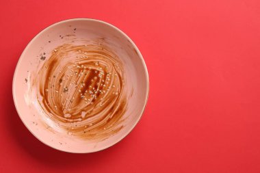 Kırmızı arka planda kirli bir tabak, üst manzara. Metin için boşluk