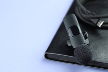 Lavalier mikrofon, kablo ve defter açık mavi arka planda, yakın plan. Metin için boşluk