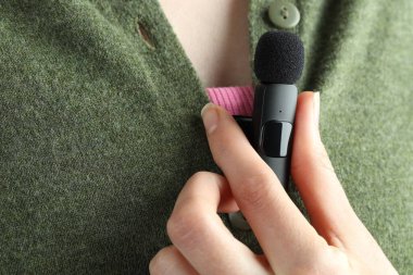 Kadın gömleğine mikrofon takıyor, yakın plan.