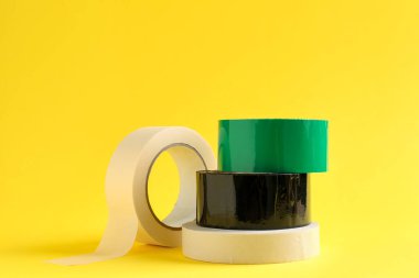 Sarı arka planda farklı yapışkan bantların ruloları