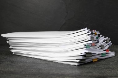 Koyu desenli masa üzerinde kağıt kağıtları olan renkli cilt ataçları, yakın plan