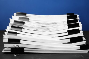 Mavi arkaplana karşı siyah tablo üzerinde kağıt sayfaları olan cilt klipleri, yakın plan