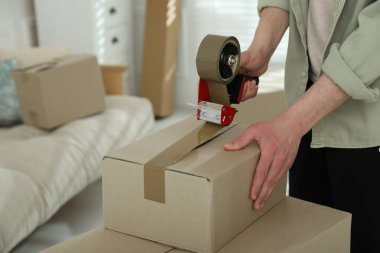 Karton kutuyu bantla kapatan adam içeride, yakın plan.