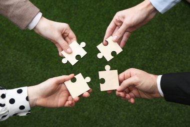 Takım çalışması. Bulanık arkaplan ve üst görünüm üzerine bulmaca parçaları koyan bir grup insan