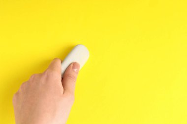 Sarı arka planda silgi kullanan bir kadın, yakın plan. Metin için boşluk