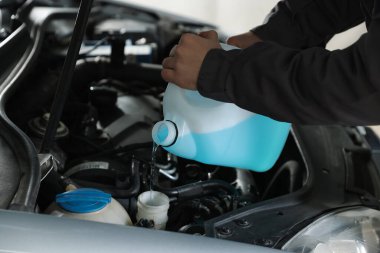 Plastik kutudan araba deposuna cam temizleyici döken adam, yakın plan.