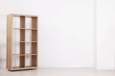 Empty wooden shelving unit near white wall indoors, space for text