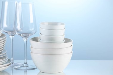 Different clean dishware on light blue background. Space for text
