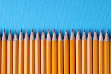 Açık mavi arka planda bir sürü kalem, üst manzara. Metin için boşluk