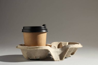 Açık gri arka planda, karton tutacakta kağıt kahve fincanı. Metin için boşluk