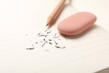 Eraser, pencil and scraps on lined notebook sheet, closeup. Space for text