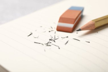 Eraser, pencil and scraps on lined notebook sheet, closeup. Space for text
