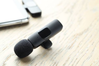 Lavalier mikrofon ve ahşap masada kablosuz alıcısı olan akıllı telefon.