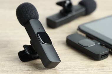 Lavalier mikrofonlar ve ahşap masada kablosuz alıcısı olan akıllı telefon.