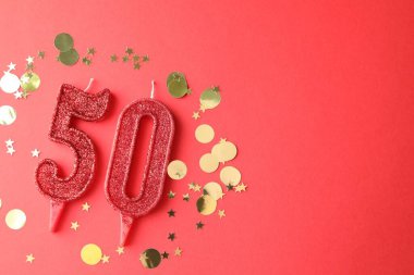 50. yaş günü. Kırmızı arkaplandaki mumlar ve konfetiler düzdü. Metin için boşluk