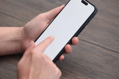 Ahşap masadaki akıllı telefondan arayan kadın, yakın plan.