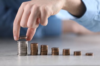 Adam açık gri masadaki bozuklukların üzerine para koyuyor, yakın plan.