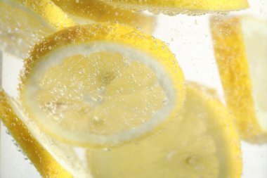 Arka planda limon dilimleri olan soda, yakın plan.