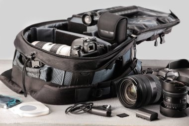 Profesyonel fotoğrafçının ekipmanı ve sırt çantası açık ahşap masada.